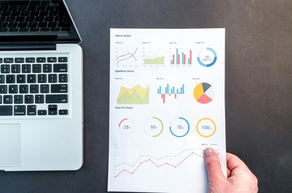 Detailed charts and graphs on a document next to a laptop, representing data analysis.